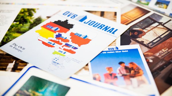 Diversi numeri storici della rivista OVB sono impilati uno sopra l'altro su un tavolo.