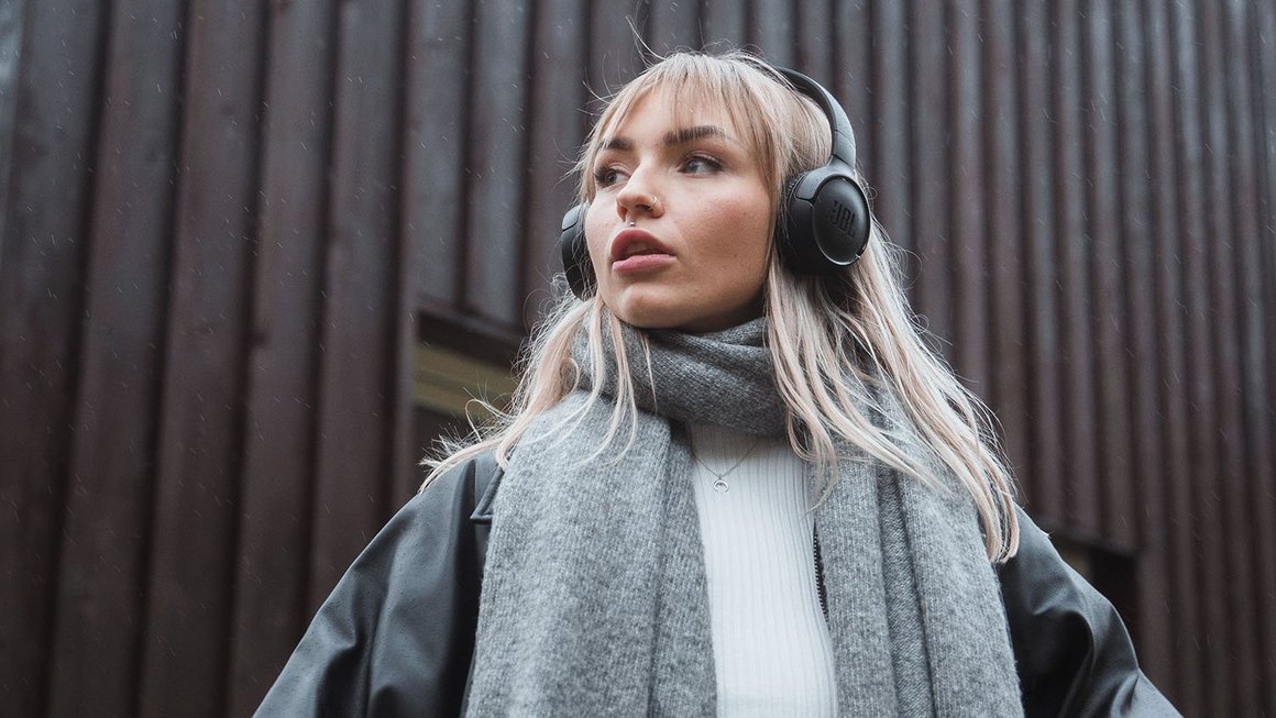 Giovane donna con le cuffie guarda in lontananza