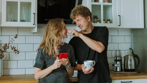 Donna e uomo sorridono in piedi in cucina – conto cointestato
