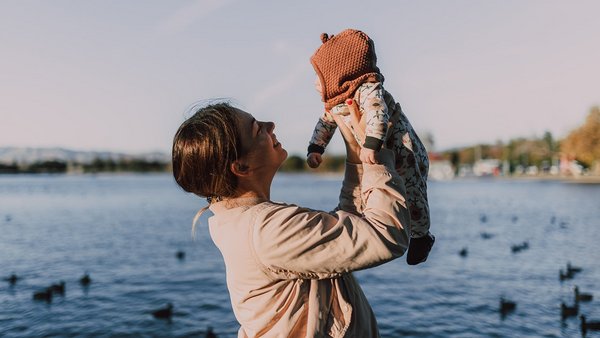 Madre tiene sollevato il suo bimbo davanti a un lago