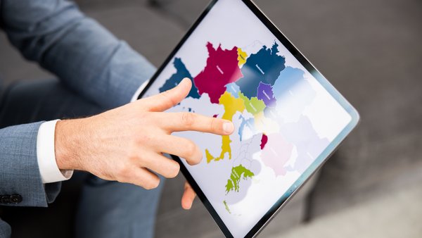 Una persona tiene in mano un tablet su cui è visualizzata una mappa dell'Europa e indica la mappa con un dito.