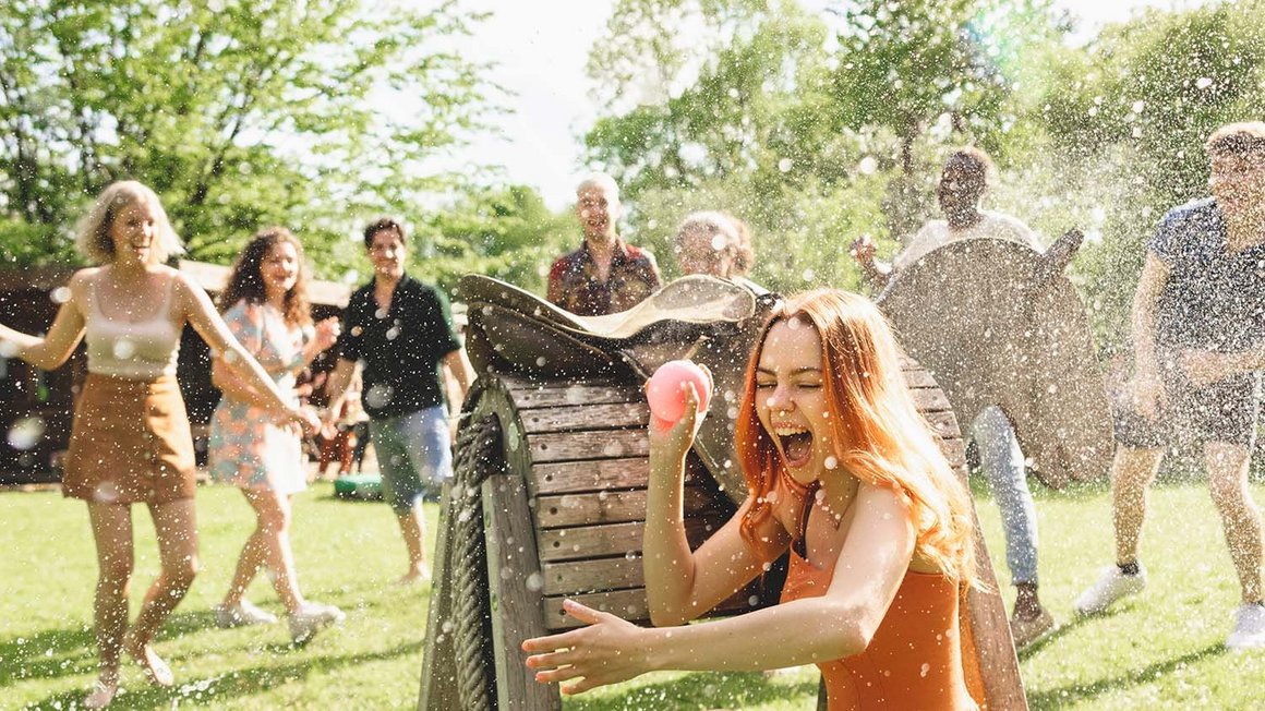 Gruppo di giovani si diverte spruzzando acqua a ragazza che si nasconde