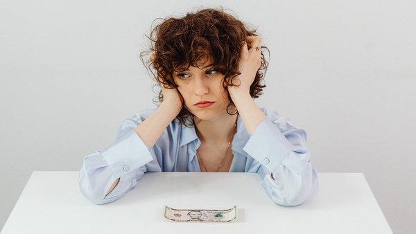 Donna pensierosa davanti a una banconota – Risparmio energetico Donna pensierosa davanti a una banconota – Risparmio energetico