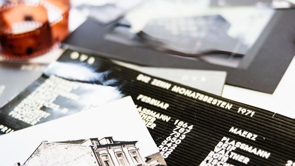 Su un tavolo sono disposte alcune stampe fotografiche d'epoca dell'edificio dell'OVB, con altri documenti sotto di esse.