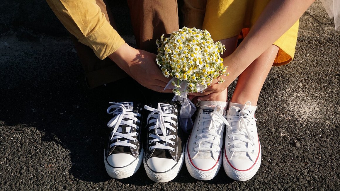 Coppia seduta sul pavimento con fiori nella mano - Wedding Planning