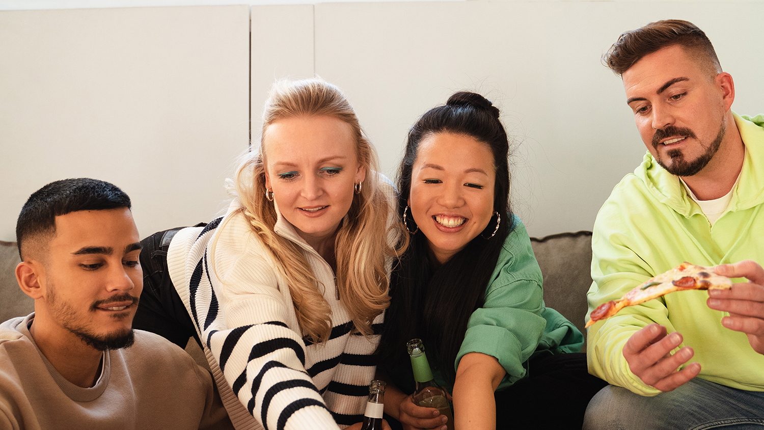 Quattro giovani sorridono seduti insieme su un divano 