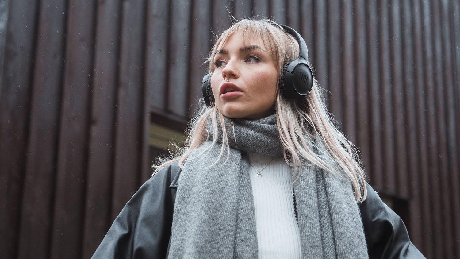 Giovane donna con le cuffie guarda in lontananza