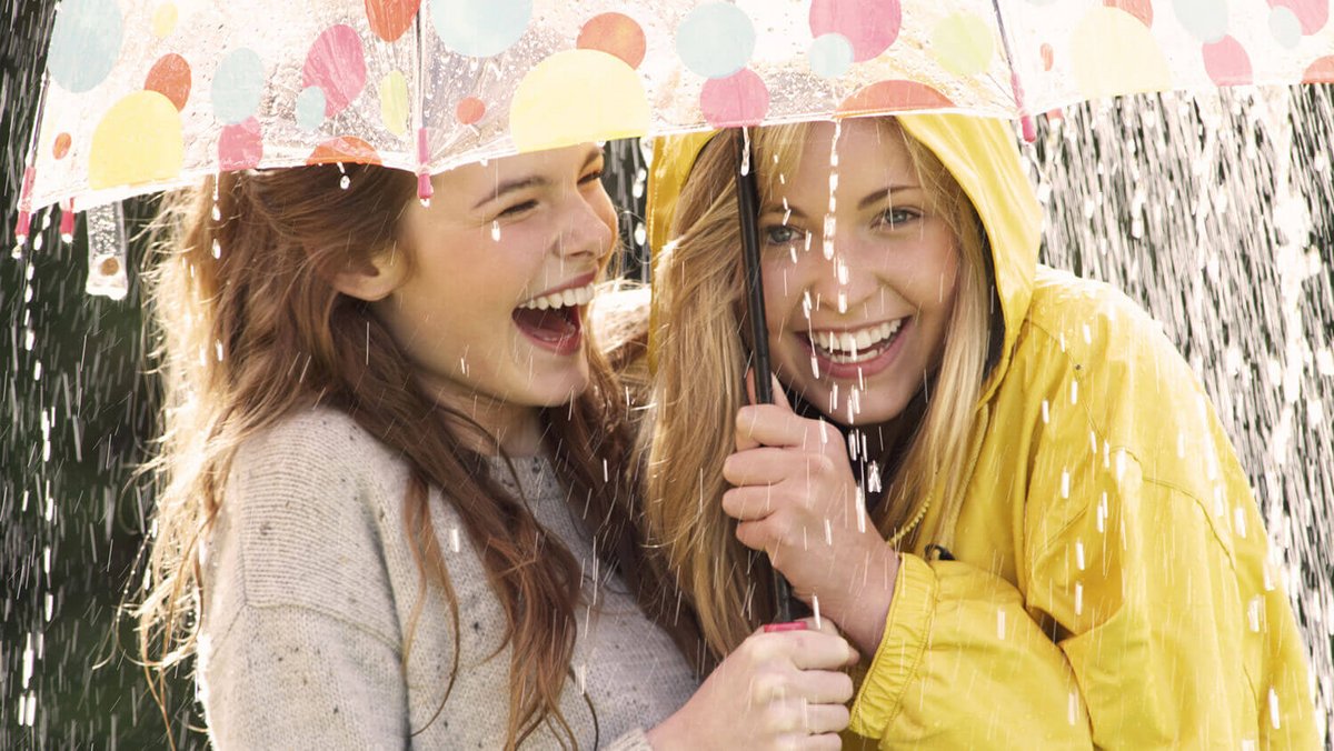 Due giovani donne sorridenti sotto l’ombrello