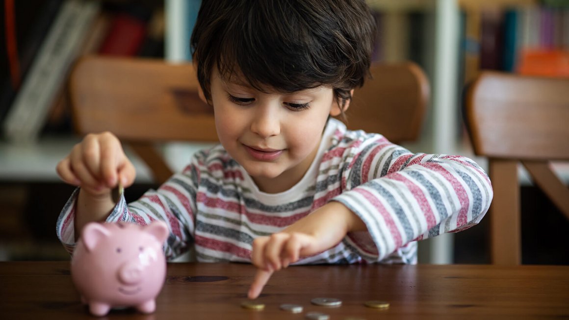 Bambino con salvadanaio e monete – spese fisse mensili per la casa