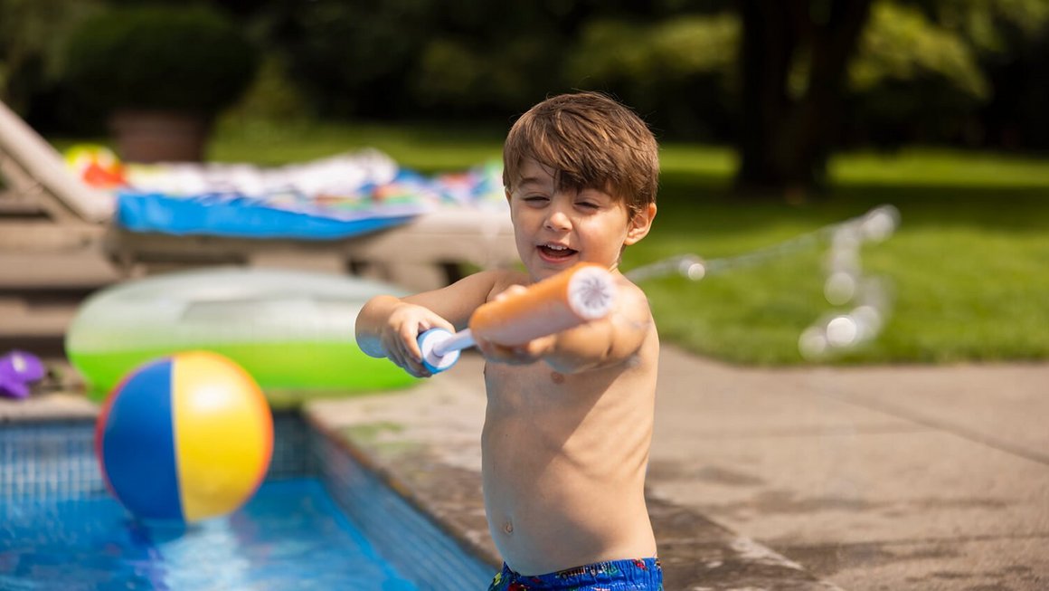Bambino in piscina con pistola ad acqua – Viaggiare sicuri  